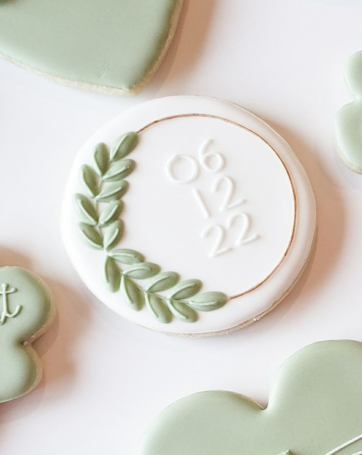 Sophisticated Round White Cookie Design with Delicate Green Leaf Motif and Elegant Gold Outline.