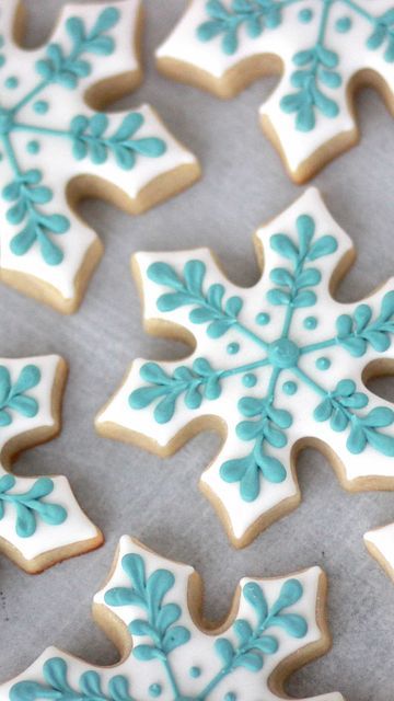 Elegant Light Blue Frosted Snowflake Cookies with Intricate Leaf Patterns for Festive Occasions.