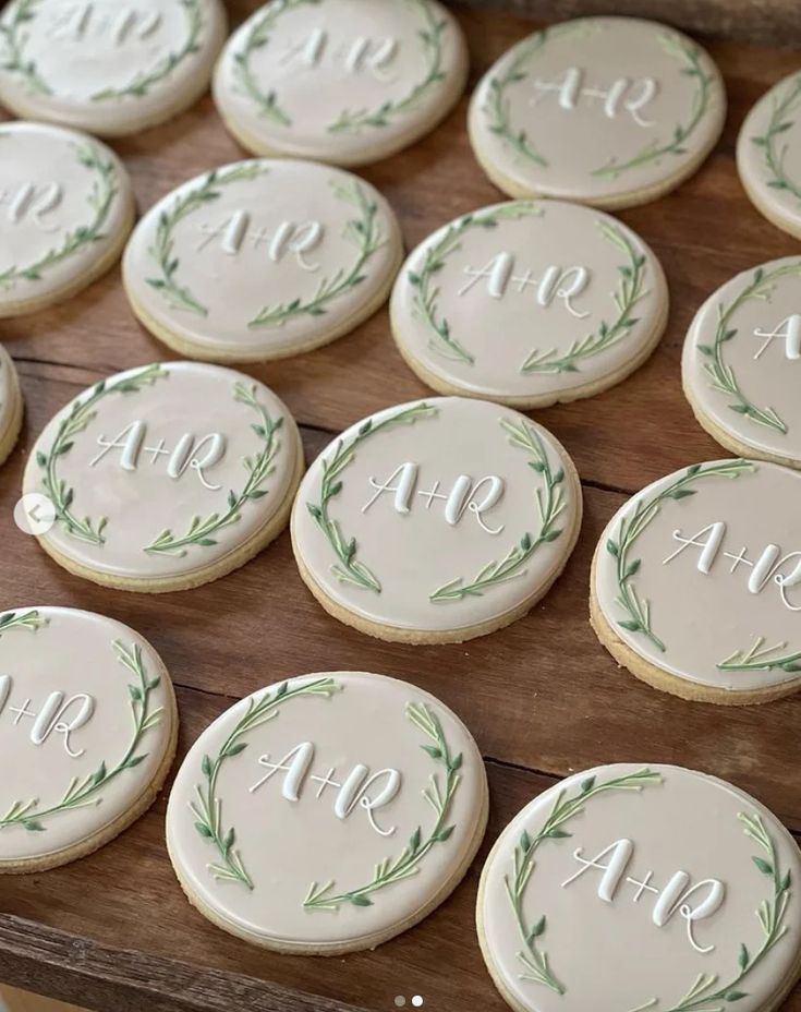 Charming Elegant Cookies: Soft Beige Icing with Green Leaf Accents and Minimalist Letter Designs for Special Occasions.