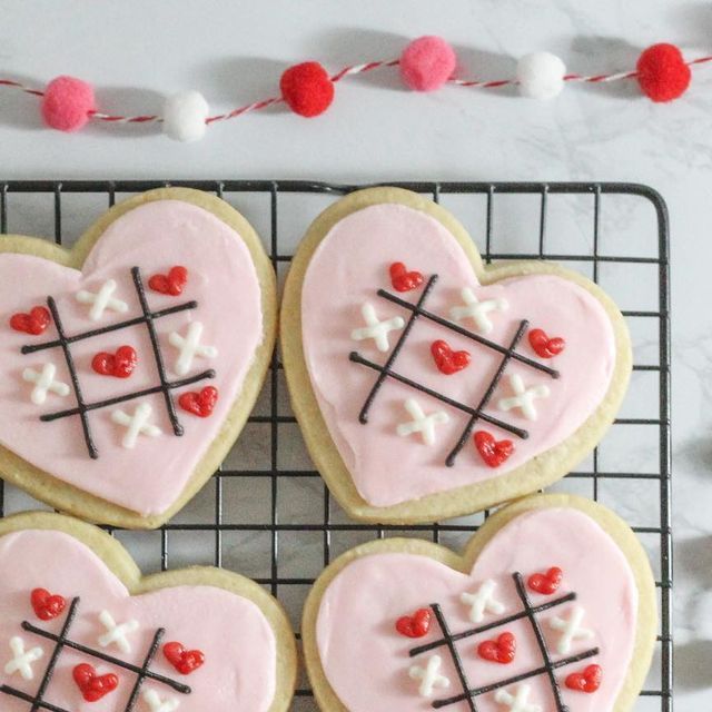 Charming Heart-Shaped Cookies with Pink Icing and Tic-Tac-Toe Designs for Festive Celebrations.