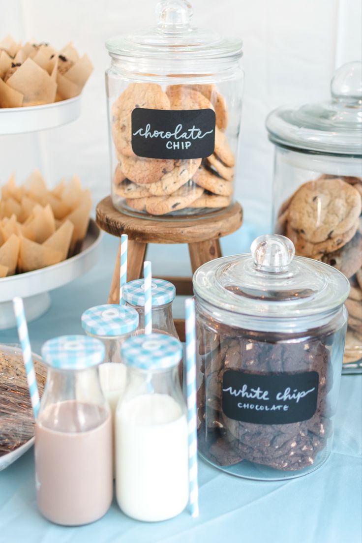 Elegant Dessert Display: Jars of Cookies and Milk Against a Cheerful Blue Backdrop.