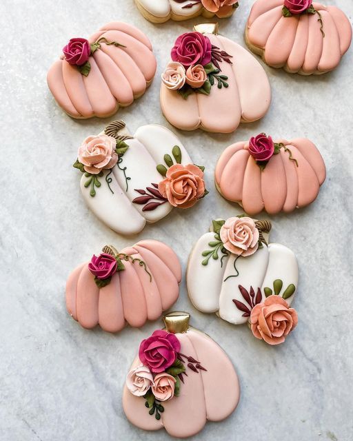 Charming Pumpkin-Shaped Cookies: An Inviting Autumn Treat Adorned with Pastel Flowers and Greenery.