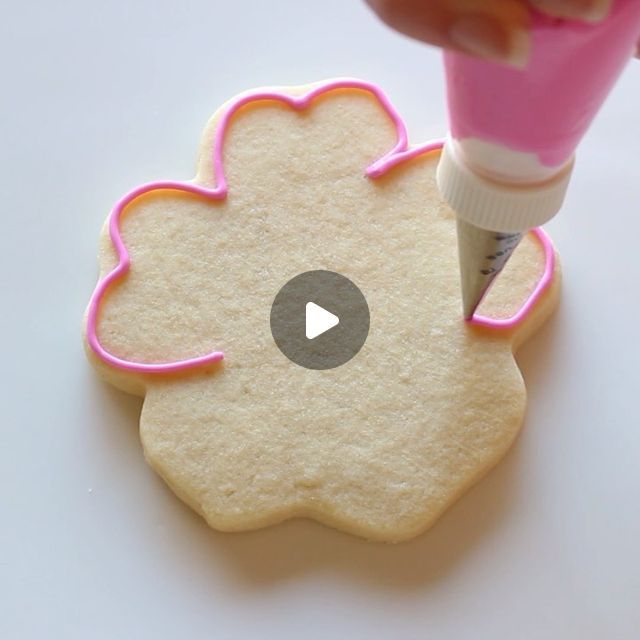 Enhancing Flower-Shaped Cookies with Intricate Pink Icing Designs.