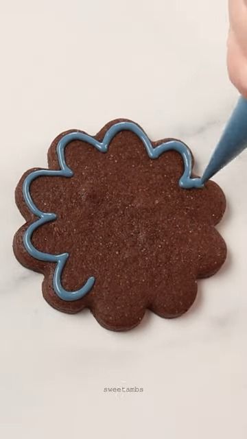 Floral Cookie Design: Artistic Chocolate Base with Skillfully Applied Blue Icing.