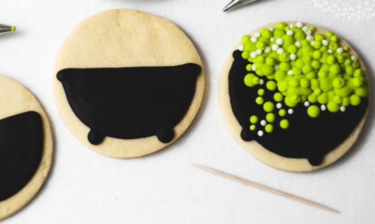 Whimsical Cauldron-Shaped Cookies with Black Fondant and Colorful Candy Pearls.