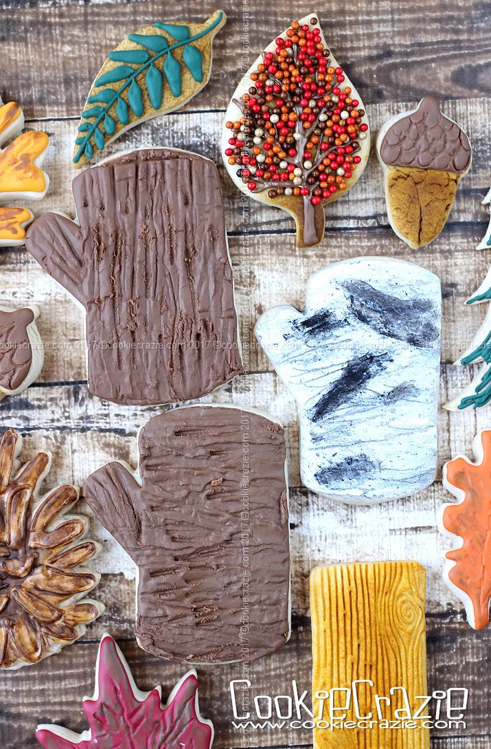 Intricate Autumn-Themed Cookie Designs Featuring Leaves, Acorns, and Mittens on a Rustic Wooden Backdrop.