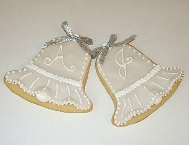 Elegant Bell-Shaped Decorative Cookies with Intricate Icing and Silver Ribbons.