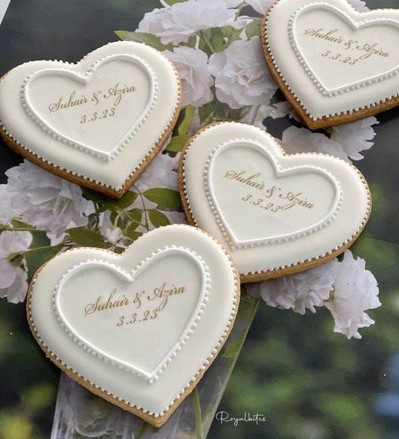 Charming Heart-Shaped Cookies with White Icing and Gold Detailing, Perfect for Celebrations.