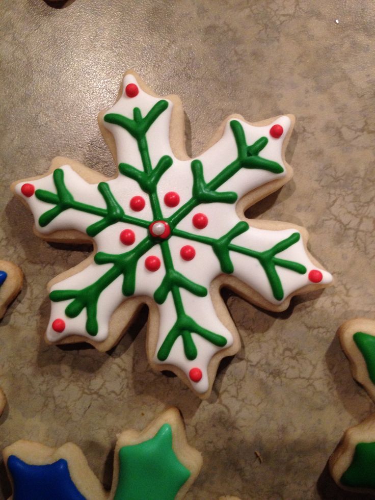 Festive Snowflake Cookie: A Winter Delight with Green Leaf Patterns and Red Berry Accents.