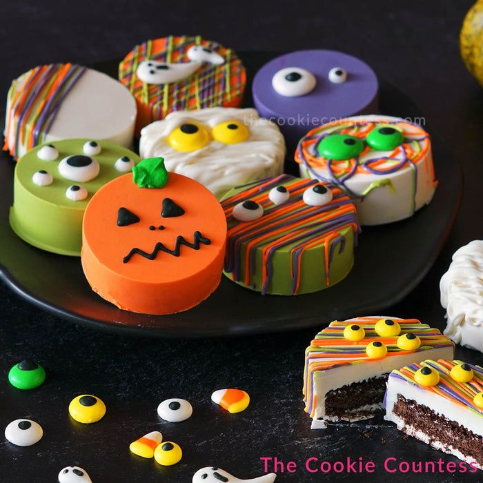 Festive Halloween Cookies with Whimsical Designs on a Black Plate.