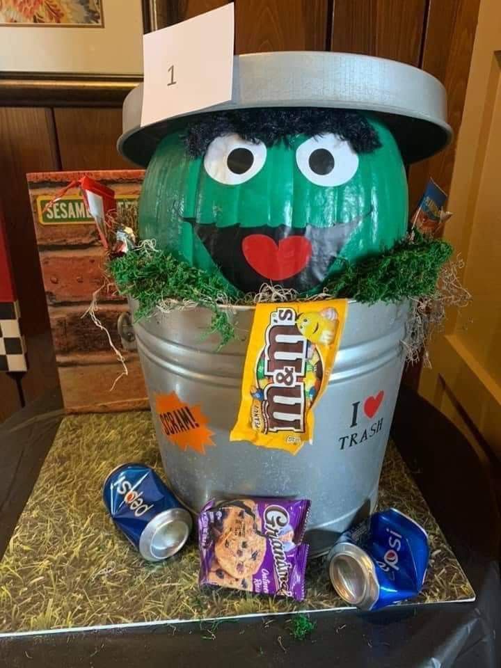 Whimsical Green Pumpkin Character Peeks from Silver Trash Can Amid Playful Snacks and Candy.