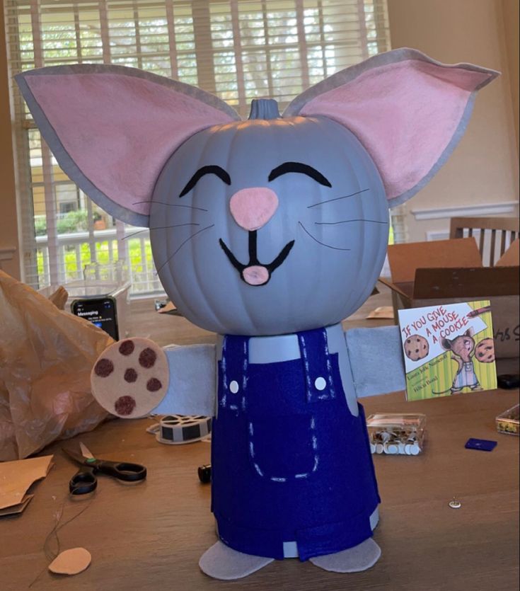 Charming Gray Pumpkin Mouse Holding a Cookie and Book in Blue Overalls.