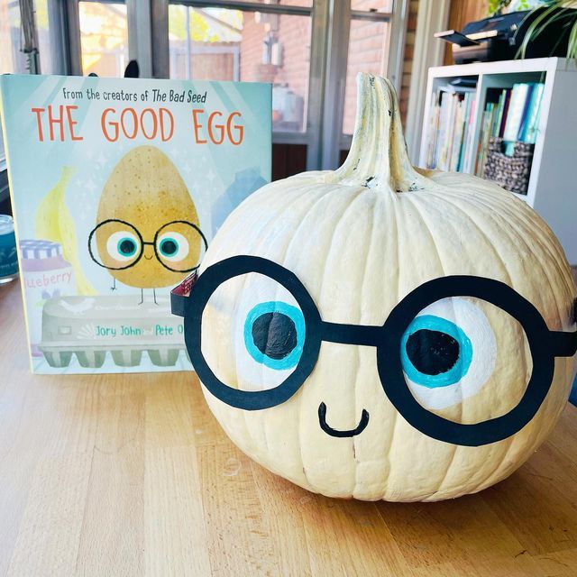 Charming Whimsical Pumpkin Decor with Cheerful Face and Children's Book for Festive Fall Appeal.