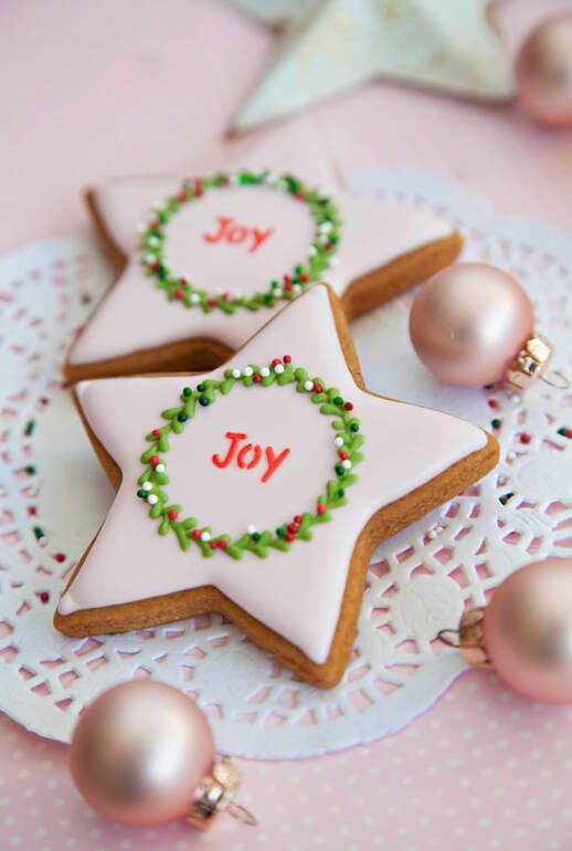 Festive Star-Shaped Cookies with Cheerful Wreath Icing and Soft Pink Ornaments.