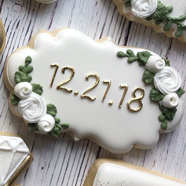 Sophisticated Cookie Design with White Icing, Green Foliage, and Golden Accents