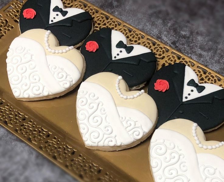 Elegant Wedding Cookies: Heart-Shaped Tuxedo and Bridal Gown Designs with Fondant Accents in Black, White, and Red.