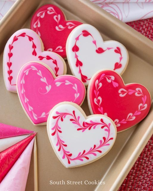 Romantic Heart-Shaped Cookies: Vibrant Pink and Red Delights with Intricate Designs for Celebrations.