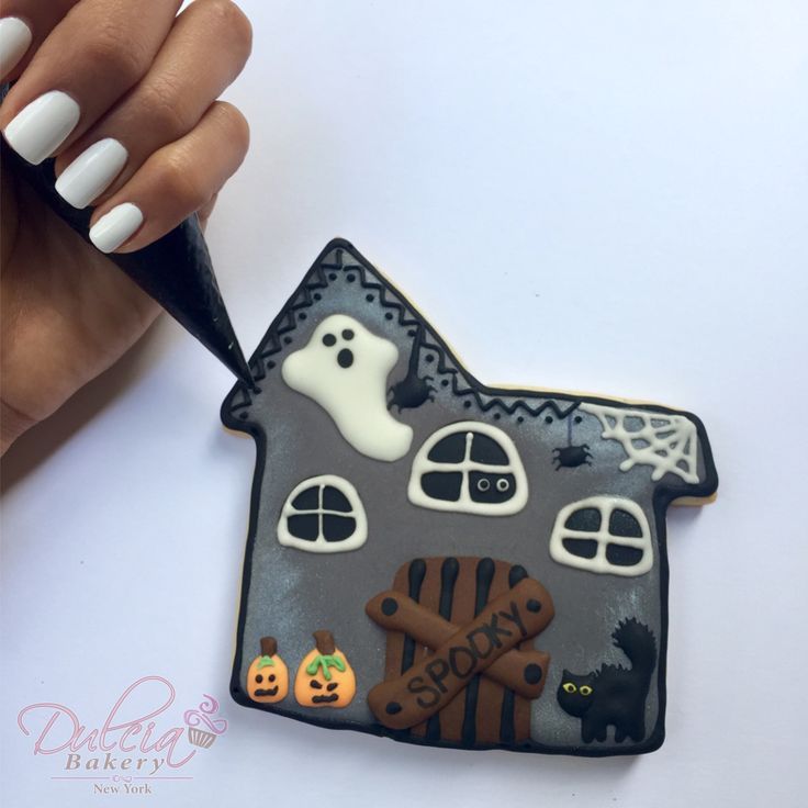 Hauntingly Whimsical: Minimalist White Nail Design Meets Festive Haunted House Cookie Decor