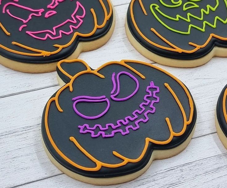 Vibrant Neon Halloween Cookies in Playful Pumpkin Designs Against a Black Background.