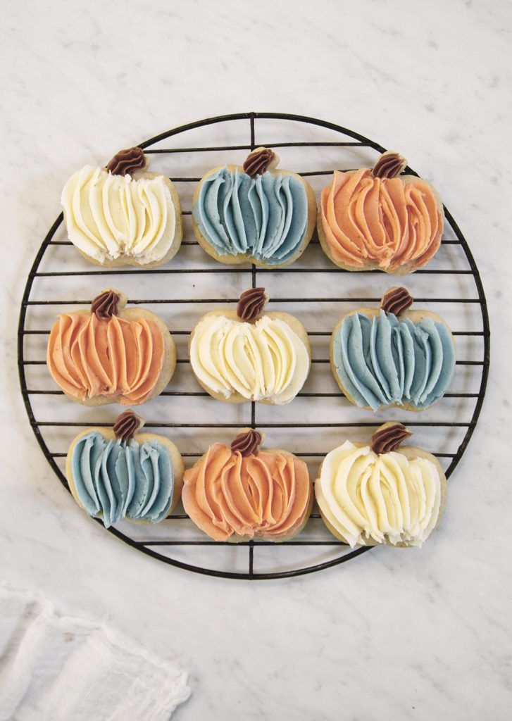 Festive Pumpkin-Shaped Cookies Showcasing Vibrant Autumn Colors on a Cooling Rack.