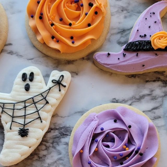 Festive Halloween Cookies: Whimsical Ghost and Witch Designs with Vibrant Frosting and Sprinkles.