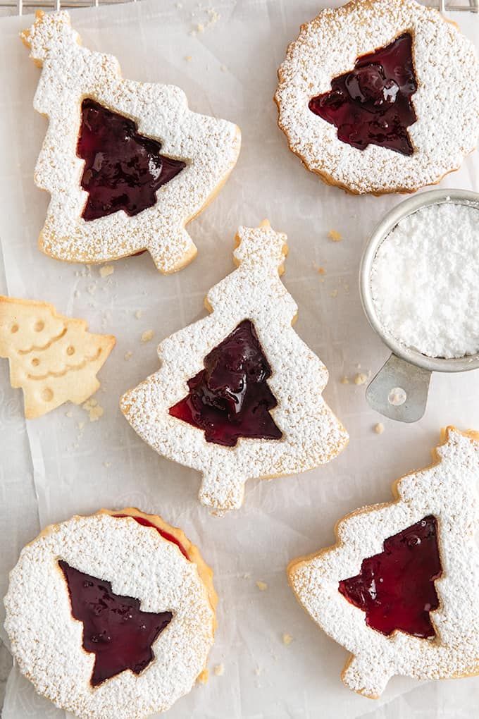 Whimsical Christmas Cookies: Tree-Shaped Delights with Berry Jelly Centers and Powdered Sugar Snow.