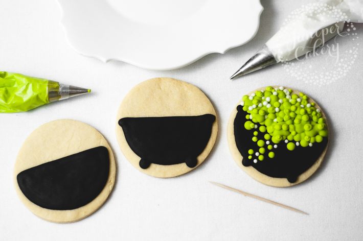 Playful Festive Cookie Designs: Black Cauldron Icing with Vibrant Green and White Accents.