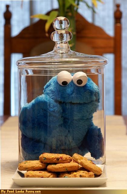 Whimsical Blue Character in Glass Jar Surrounded by Colorful Cookies Evokes Nostalgia and Humor.