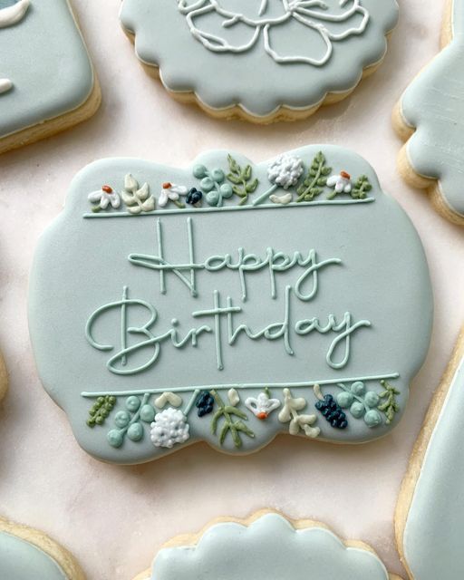 Charming Floral Birthday Cookie Design on Soft Pastel Blue Background.