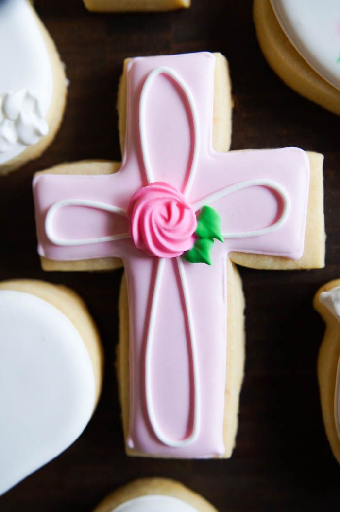 Festive Decorative Cross-Shaped Cookie with Pink Icing and Floral Accents.