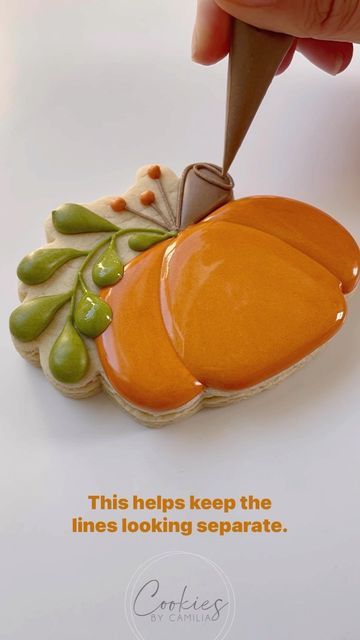 Vibrant Pumpkin-Shaped Cookie Design Enhanced with Green Leaves and Intricate Piping for Autumn Celebrations.