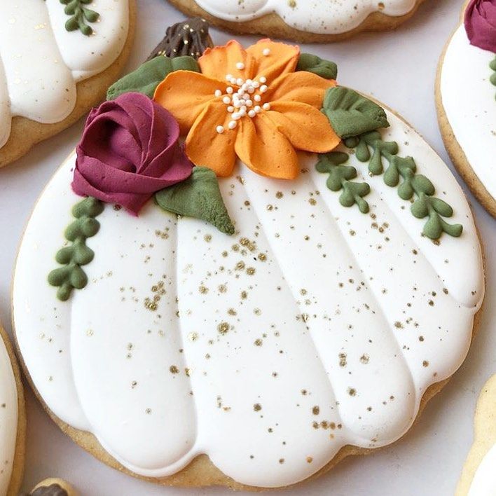 Elegant Pumpkin-Shaped Cookies with Vibrant Floral Accents and Festive Gold Sprinkles.