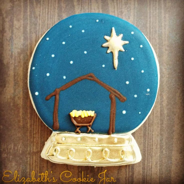 Festive Snow Globe-Themed Decorative Cookie with Cozy Stable and Elegant Gold Accents.