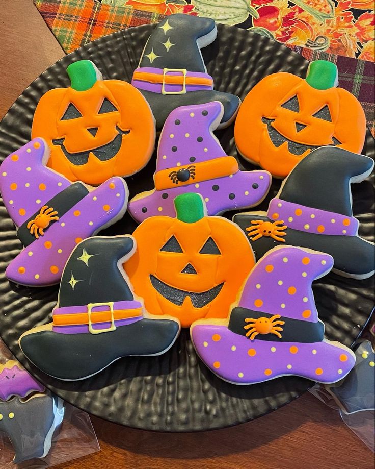 Festive Halloween Cookies: A Whimsical Assortment of Jack-o'-Lanterns and Witches' Hats on a Black Plate.