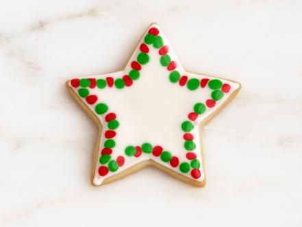 Cheerful Star-Shaped Cookie Design: Festive White Icing with Red and Green Dots for Nail Art Inspiration.