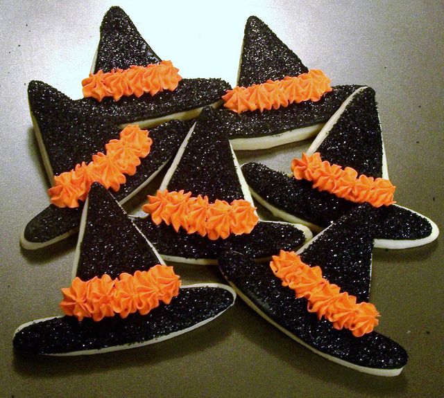 Playful Witch Hat Cookies: Festive Treats with Glossy Black Icing and Vibrant Orange Frosting for Halloween.